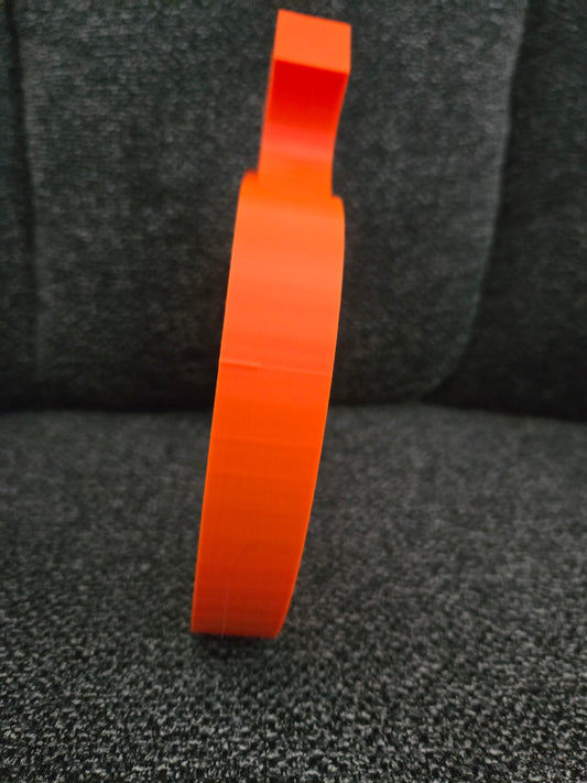 Side profile view of 3D printed Swirly Pumpkin showing thickness and stem detail in solid orange