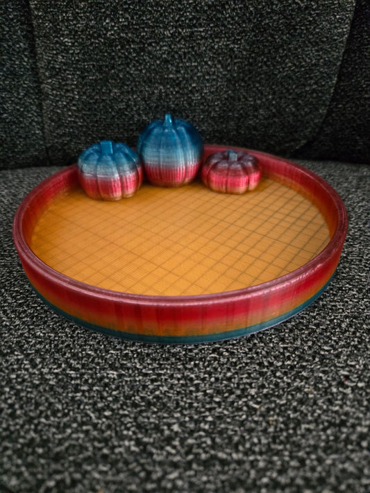 3D printed Harvest Moon Pumpkin Tray with three mini pumpkins in blue-to-red gradient filament on a warm orange grid-textured round tray