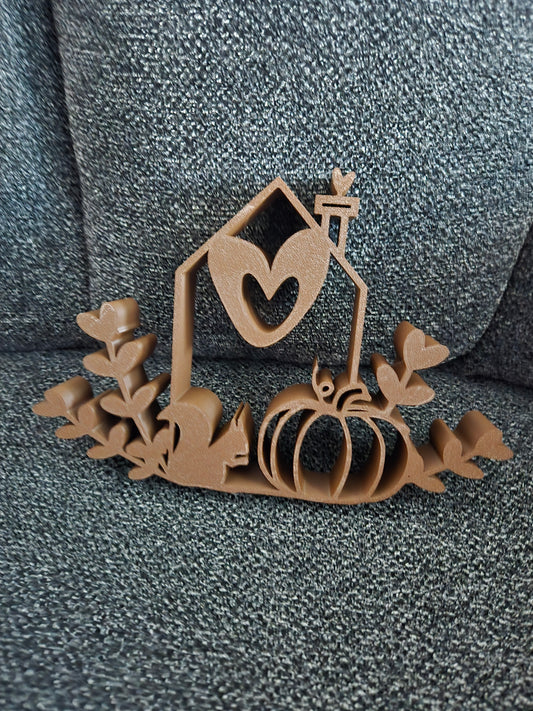 3D printed Home Sweet Harvest House in warm brown filament showing open-frame cottage silhouette with heart window, lantern, pumpkin, and ivy leaves, front view
